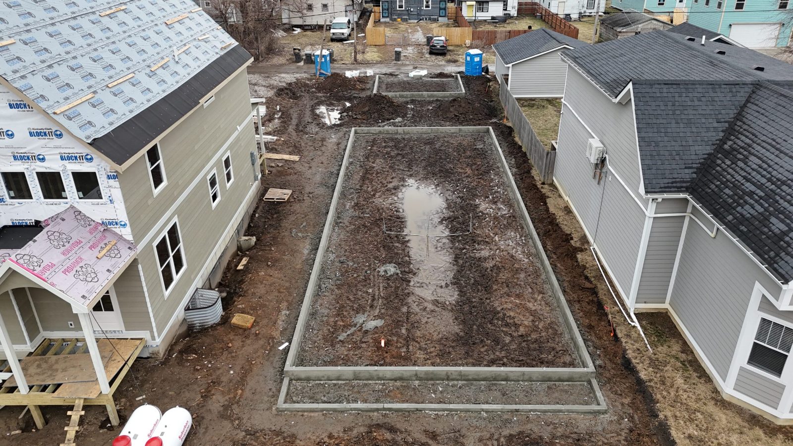 Aerial view of a completed foundation between two finished homes