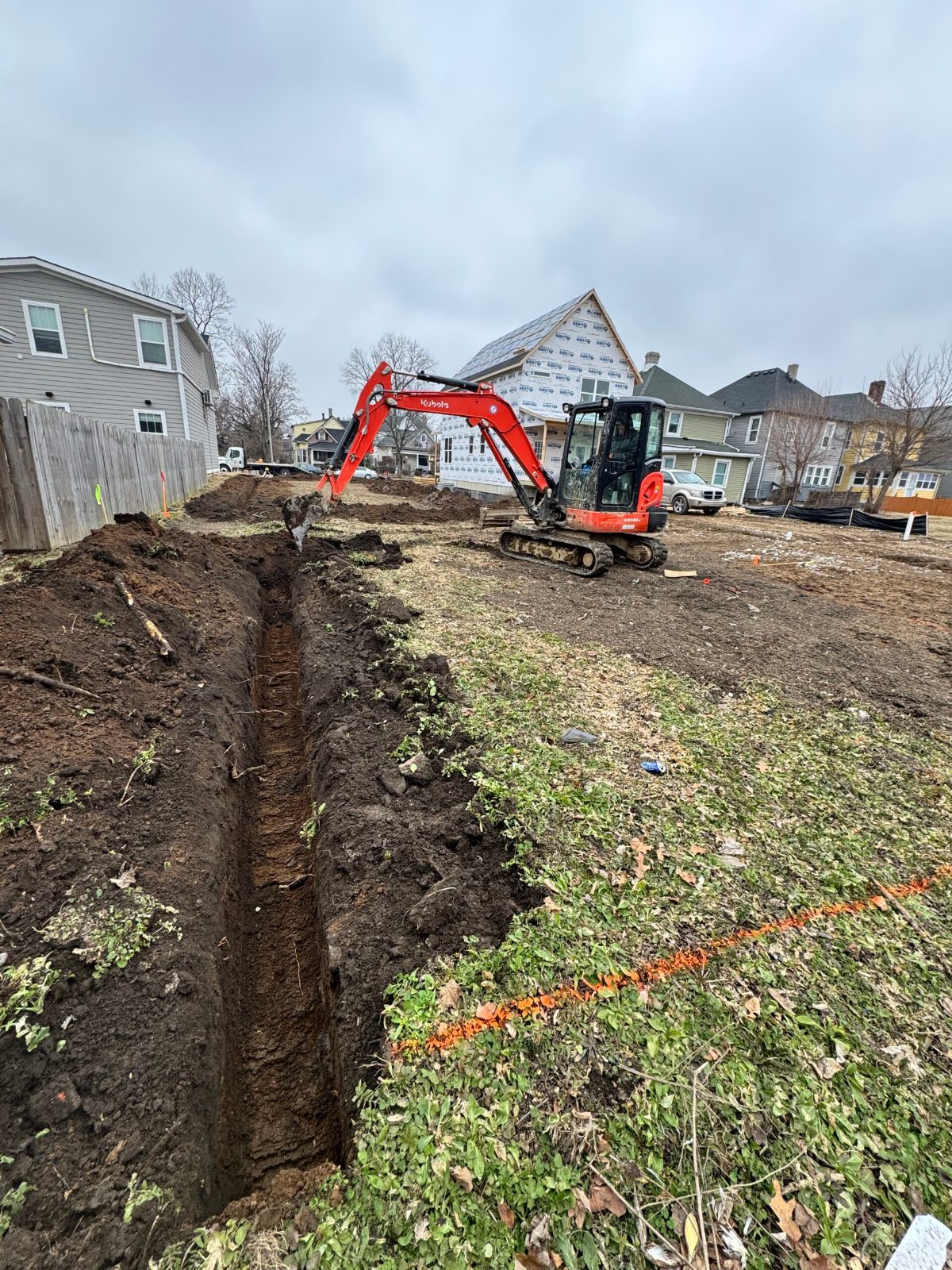 Excavator digging foundation trenches on a residential lot
