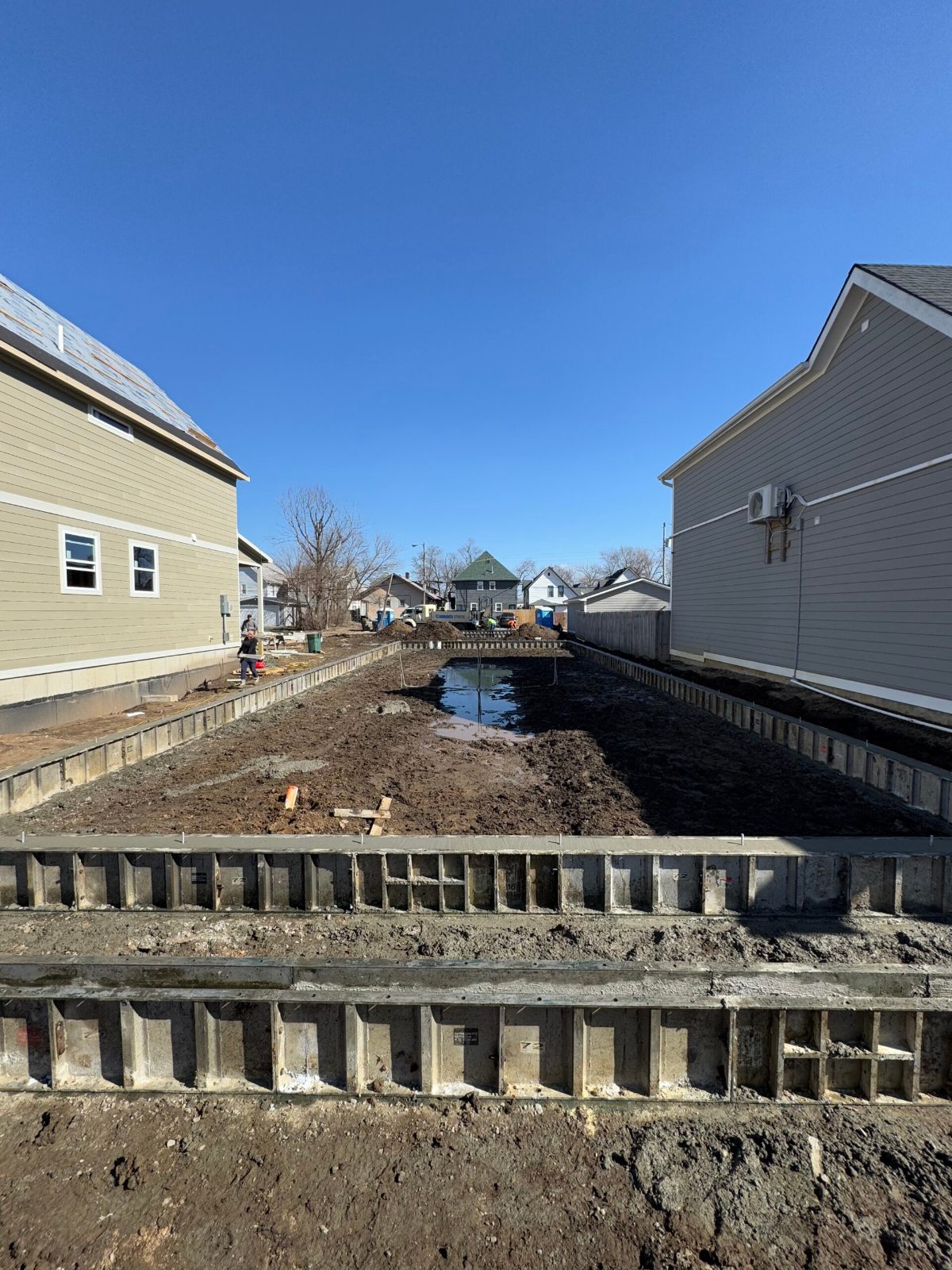 New construction site with concrete forms between two completed homes
