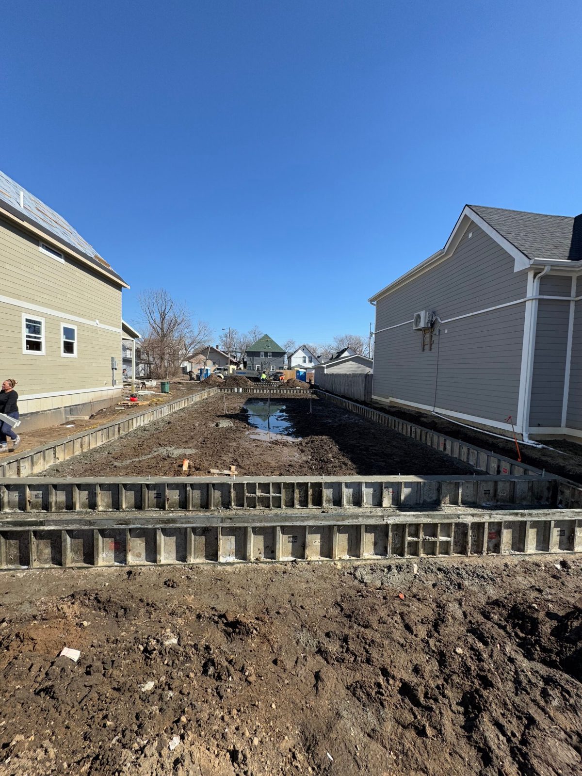 Aluminum concrete forms set and braced along a foundation perimeter under a clear blue sky